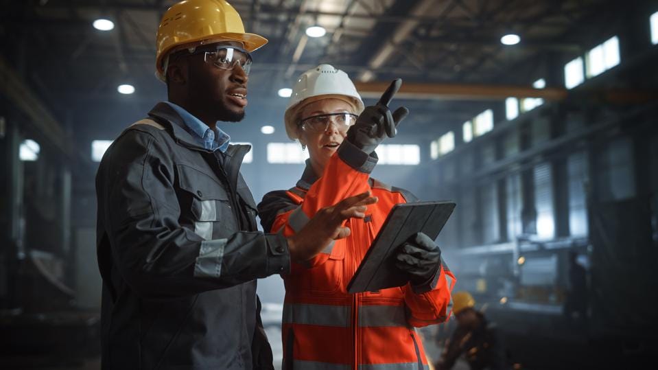 Two workers in a factory with hardhats